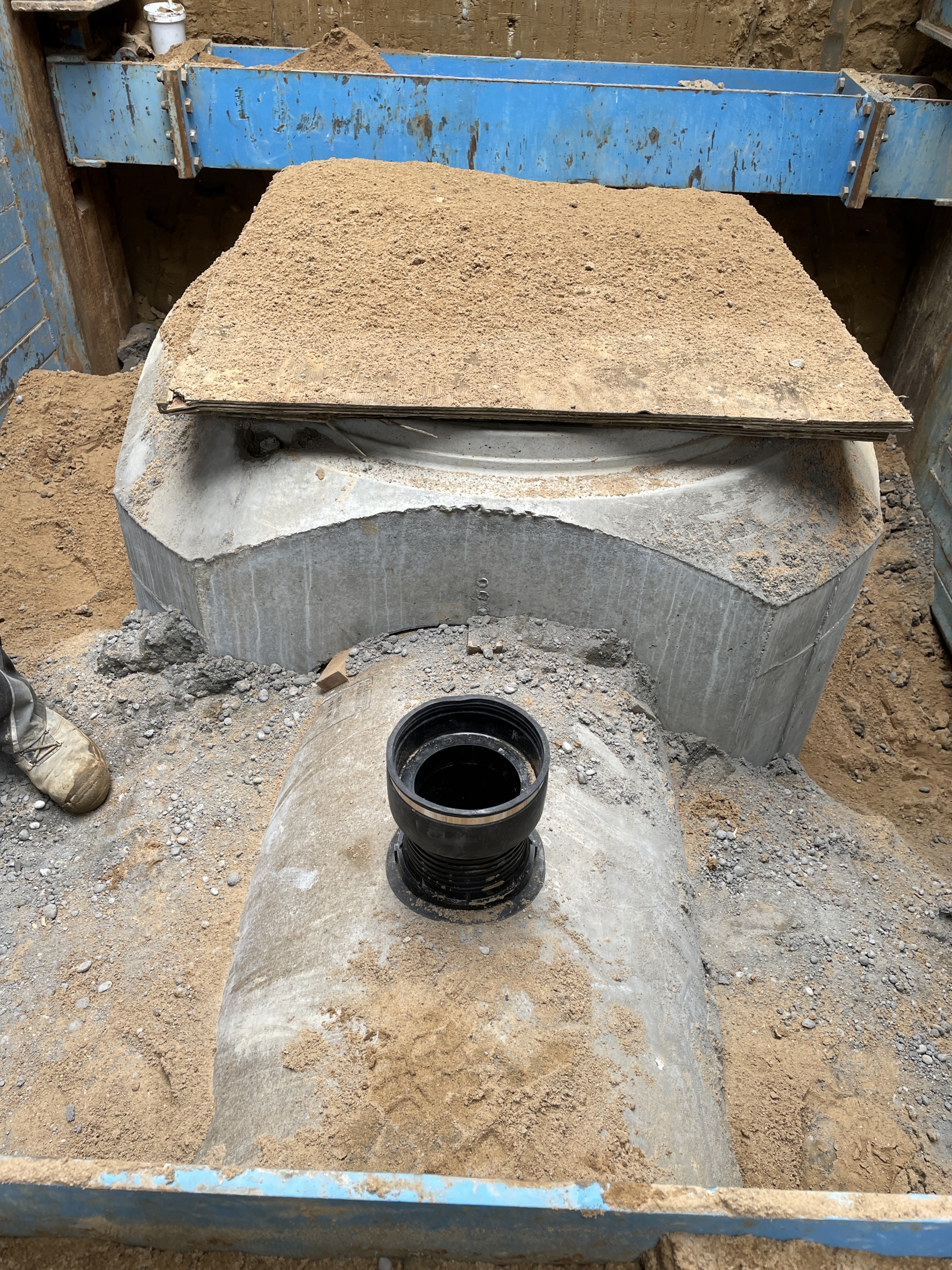 Foto von einer Baustelle. Ein teilweise ausgegrabenes Betonrohr wurde direkt neben einem Kanalschacht mit einem Anschlusselement versehen.